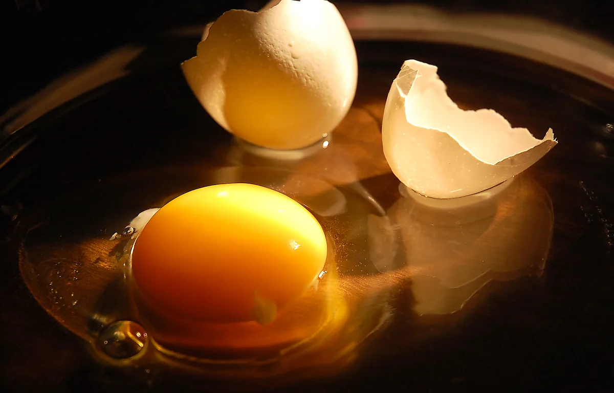A raw chicken egg cracked open into a bowl, a complete protein containing all essential amino acids